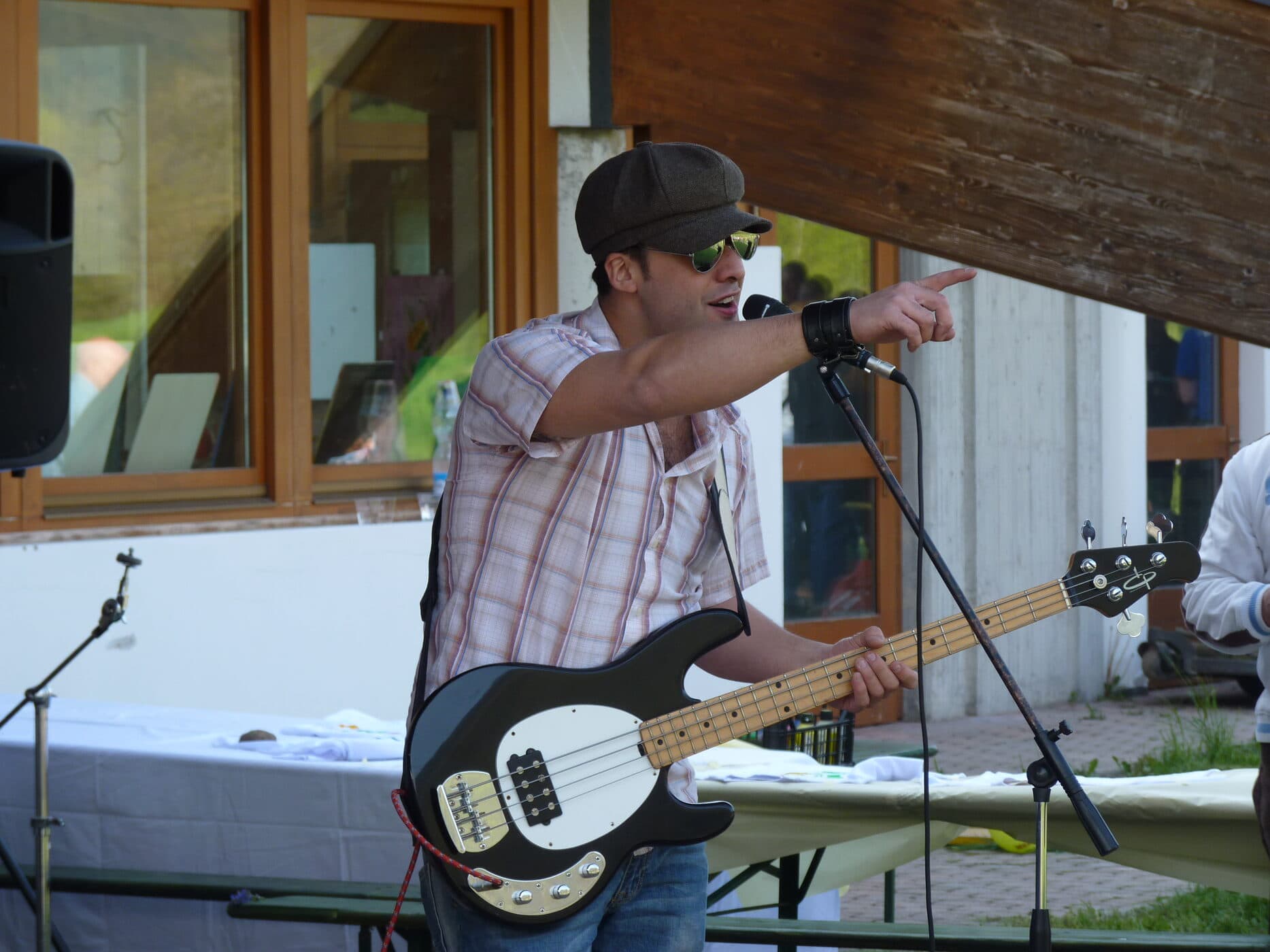 Osman Meyredi pointing to the crowd, bass guitar in hand, at an outdoor show in Italy