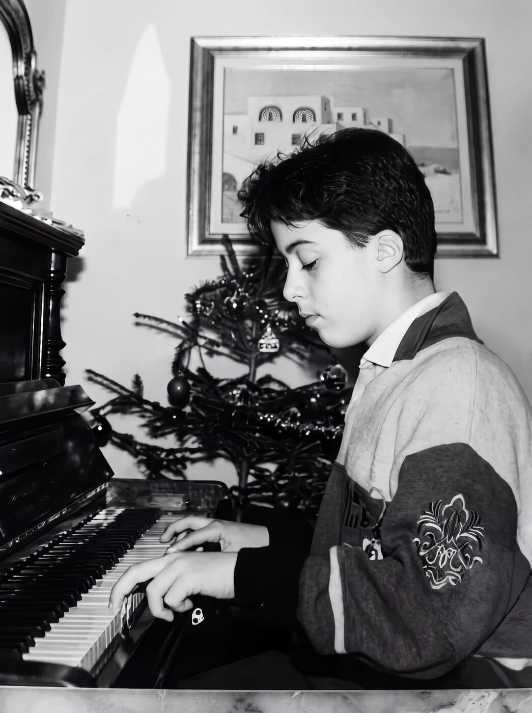 Osman Meyredi as a child playing an upright piano, black and white